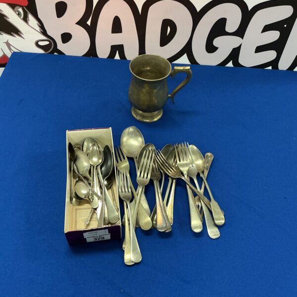 Vintage silverplate cutlery set and tankard on display.