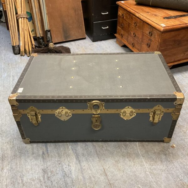 Front view of a vintage steamer trunk with metal clasps.