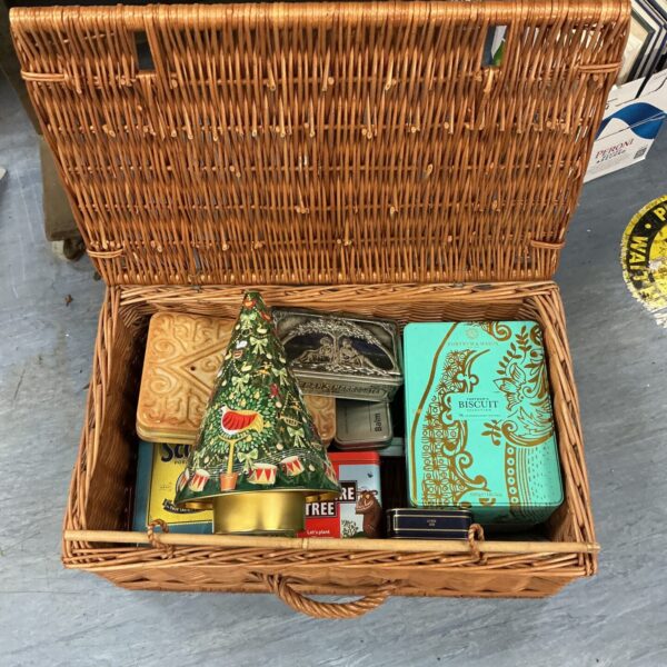 Wicker basket overflowing with vintage collectible advertising tins.