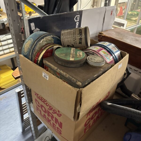 Assorted vintage tins in a cardboard box, collectible metal storage.