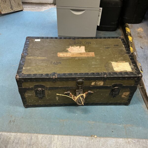 Front view of a weathered vintage travel trunk with metal accents.