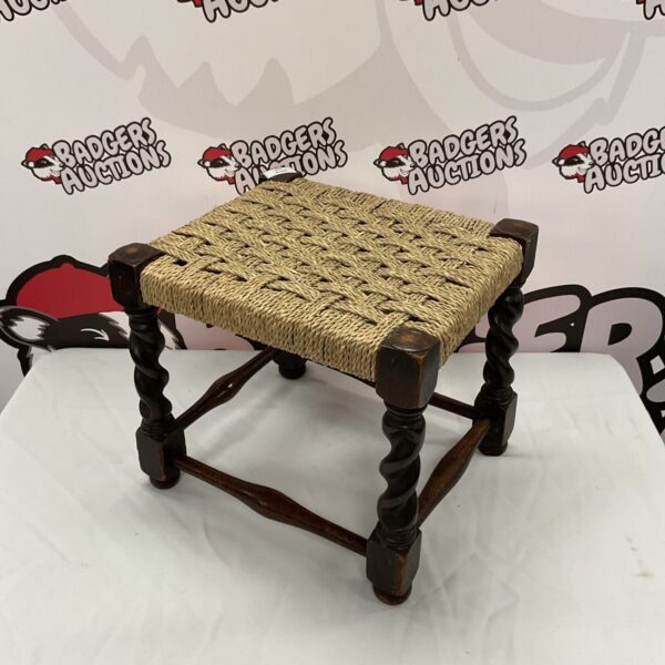 Vintage wicker stool with turned wooden legs and woven seat.