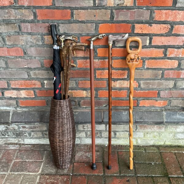 Vintage walking sticks and umbrella in wicker stand.
