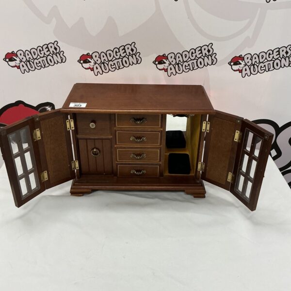 Vintage wooden jewellery cabinet with doors open, displaying drawers.