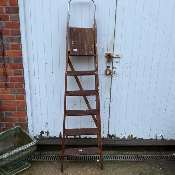 Vintage wooden step ladder leaning against a wall.