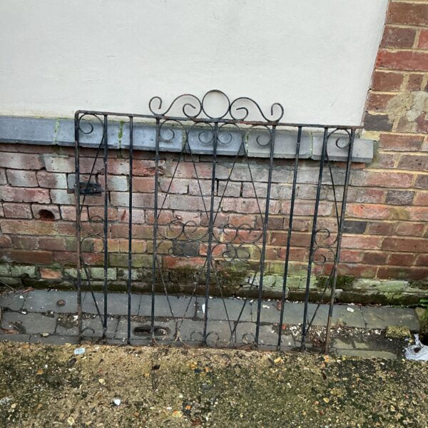 Antique wrought iron garden gate with decorative scrolls.