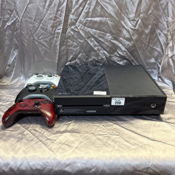 Xbox One console with Gears of War and Xbox 360 controllers.