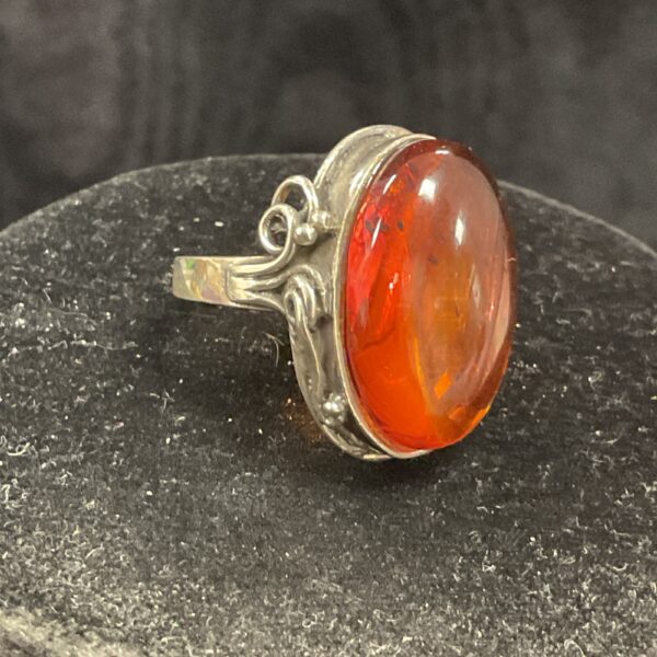 Close-up of a 925 silver amber ring with a vibrant orange stone.