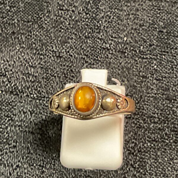 Close-up of a 925 silver ring with a warm amber stone.