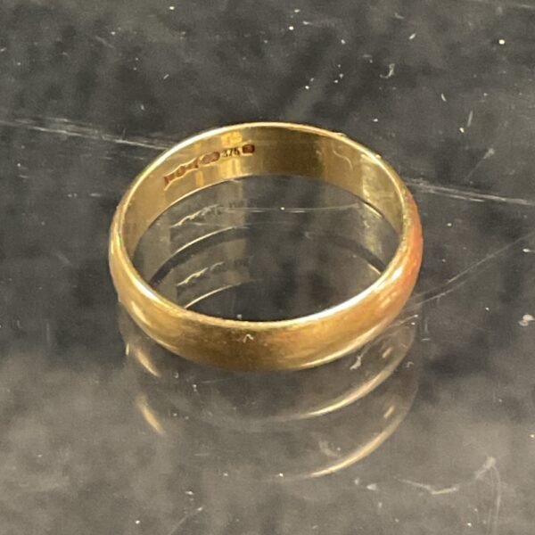 Close-up of a 9ct gold wedding ring with a plain band.