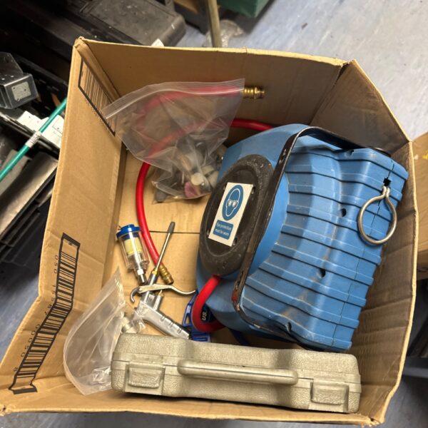 Used air hose reel in a tray of workshop tools.
