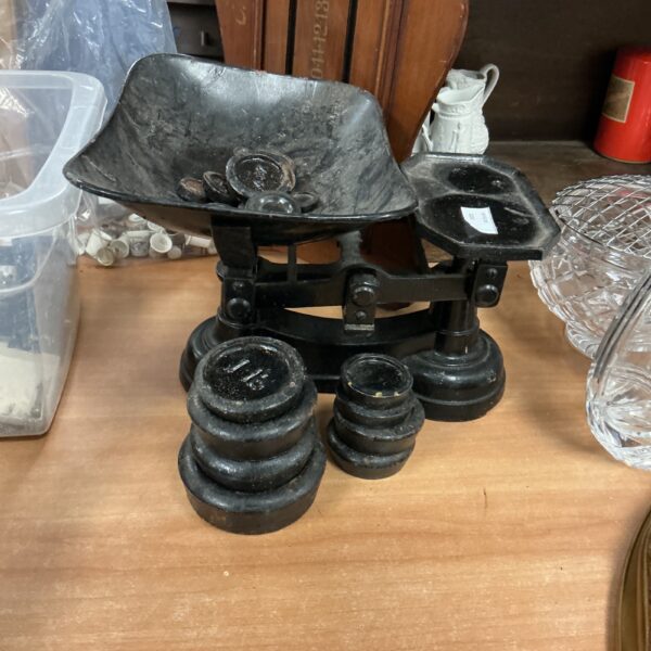 Antique black metal kitchen balance scales with weights for measuring.