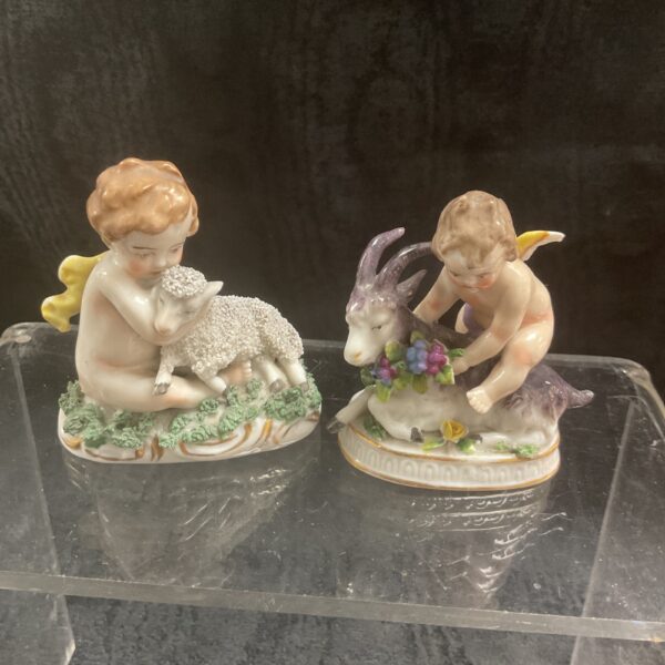 Antique porcelain figurine of a cherub embracing a lamb.