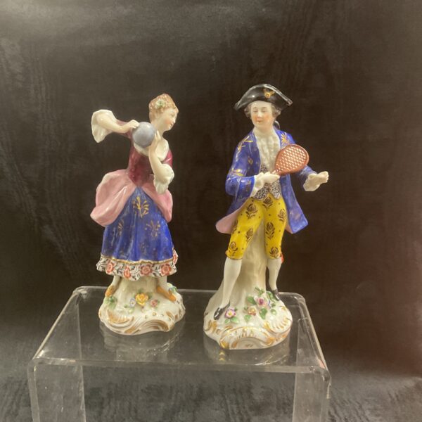 Antique porcelain figurines of a couple in 18th-century attire.