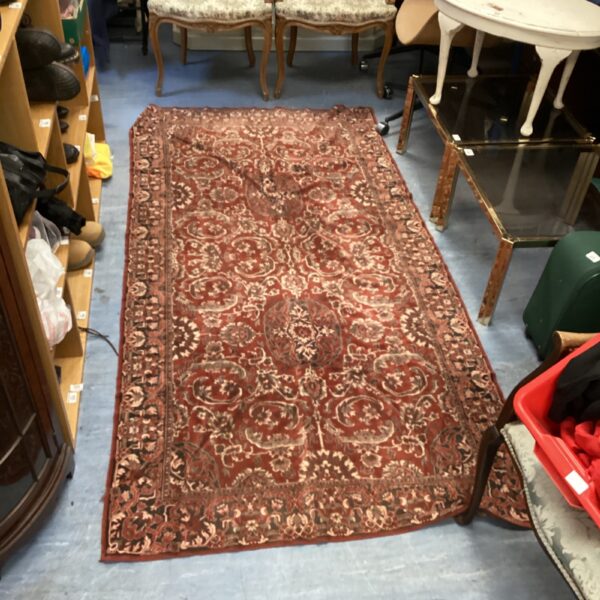 Antique rug with intricate floral design and rich red tones.