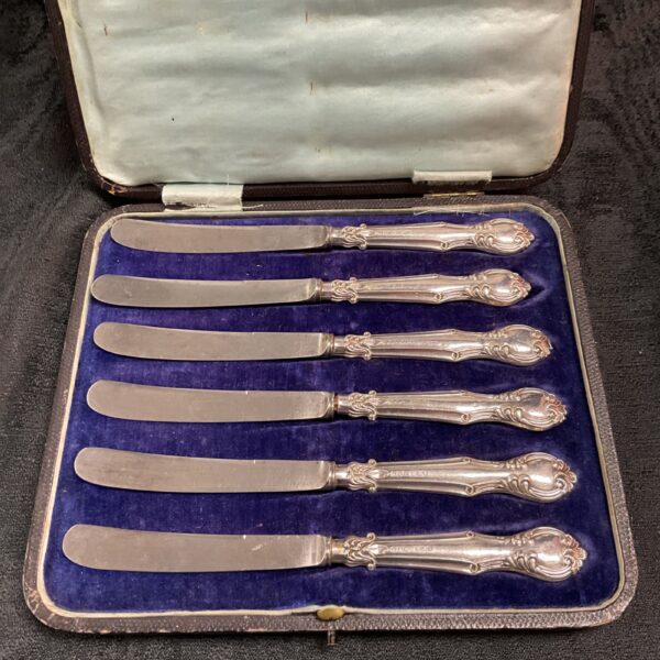 Antique silver butter knives in a velvet case, vintage cutlery set.
