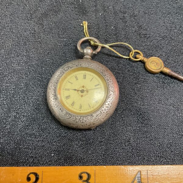 Antique silver pocket watch with engraved case and Roman numeral dial.