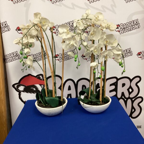 Pair of artificial potted plants with white blooms on a table.