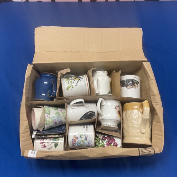 Assorted ceramic mugs in a cardboard box, collectible tea and coffee cups.
