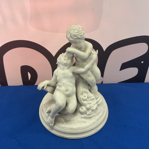 Antique bisque porcelain cherubs enjoying a grape harvest, vintage figurine.