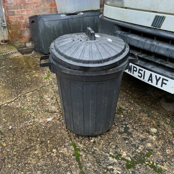 Black plastic garden bin for outdoor storage and waste.