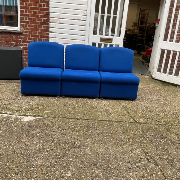Three blue padded seats in a public space.
