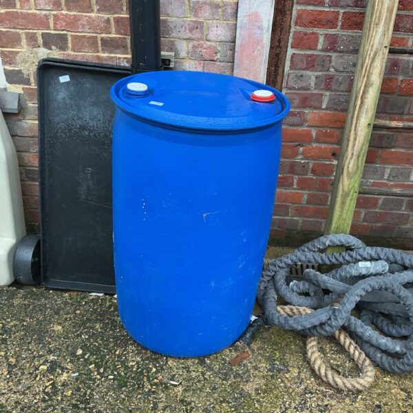 Blue plastic water butt in a garden setting for rainwater collection.