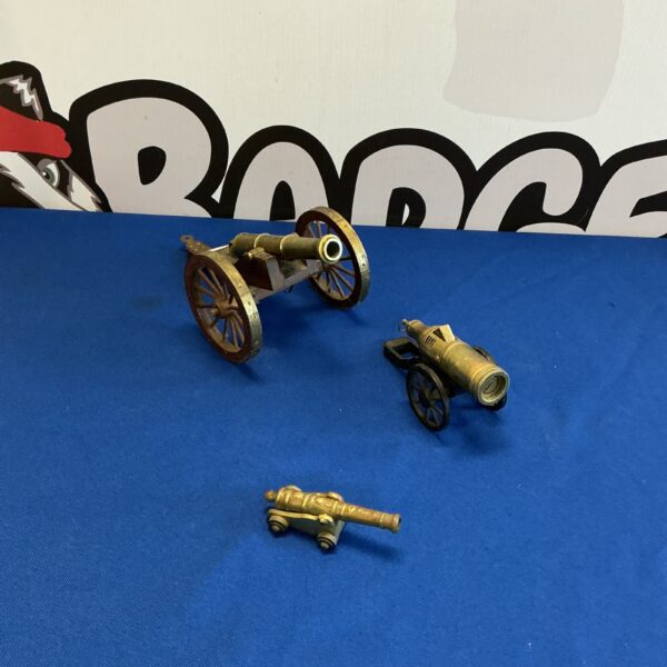 Set of three antique-style brass cannon ornaments for collectors.