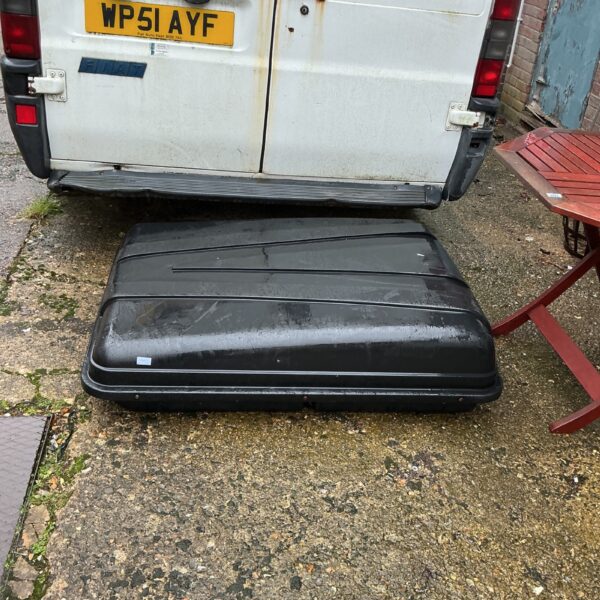 Black car roof box mounted on a vehicle exterior.