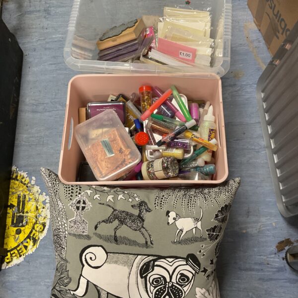 Crafting supplies lot with glitter pens, glue, and a pug pillow.