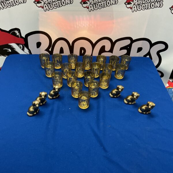 Gold decorative shot glasses with miniature dog ornaments on display.