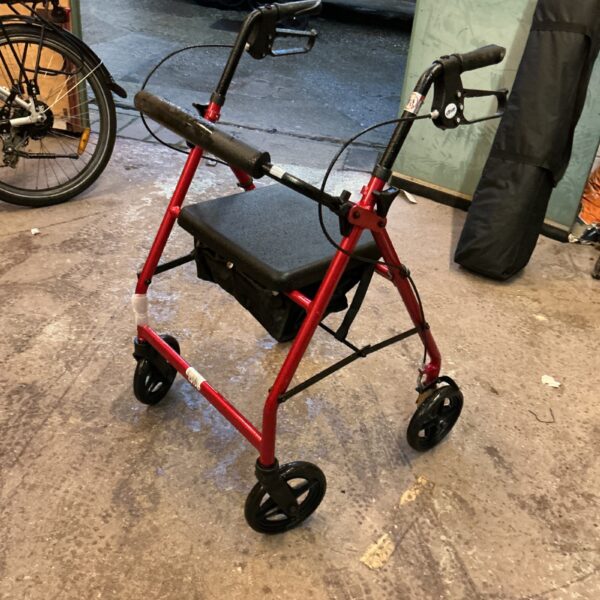 Red Drive walking trolley with a seat and basket for mobility assistance.