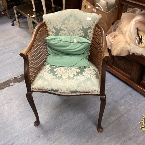 Elegant Edwardian rattan armchair with green patterned upholstery.