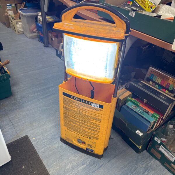 Yellow Exin site light with metal cage, showing wear.