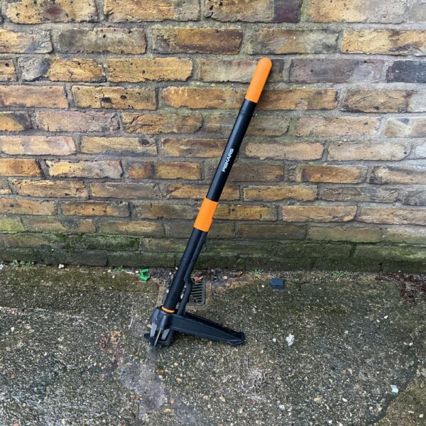Orange and black Fiskars weed puller for garden use.