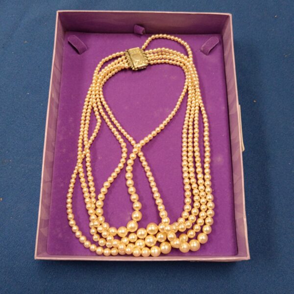 Five strand faux pearl necklace displayed on purple background.