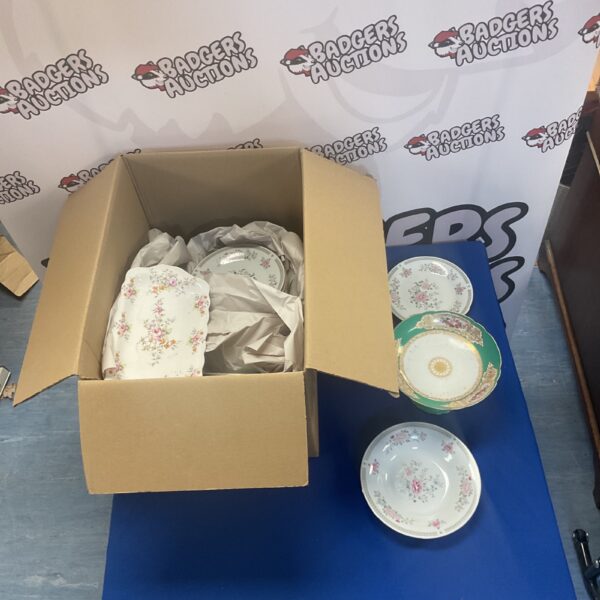 Box of vintage floral porcelain crockery on a blue table.