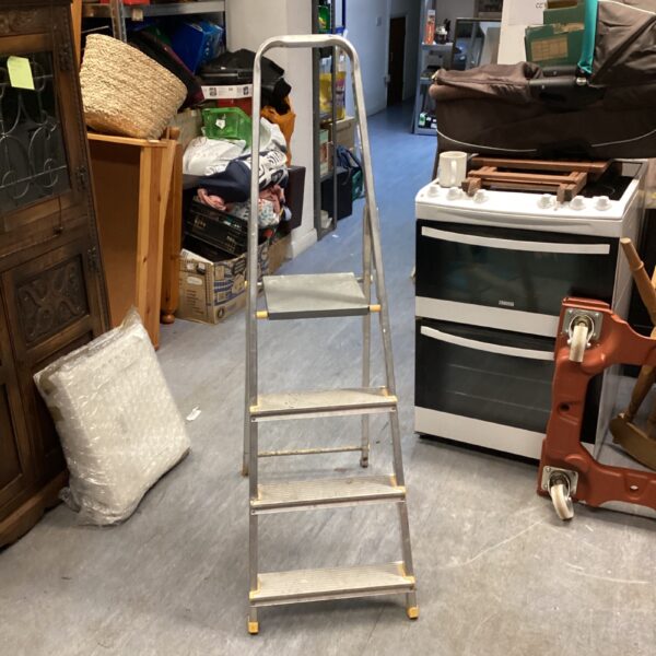 Silver folding metal step ladder against a wall.
