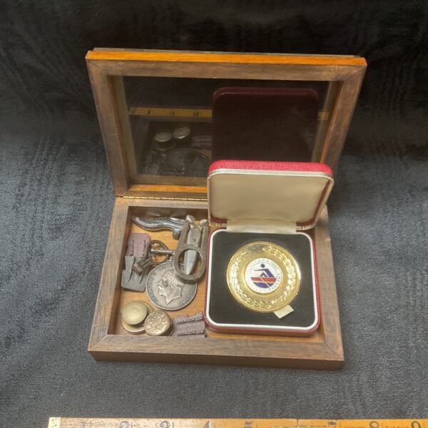Open view of a vintage framed medal and coin box with contents visible.