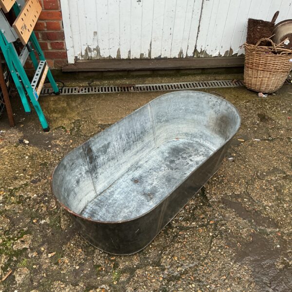 Vintage galvanised bath tub in a garden setting.
