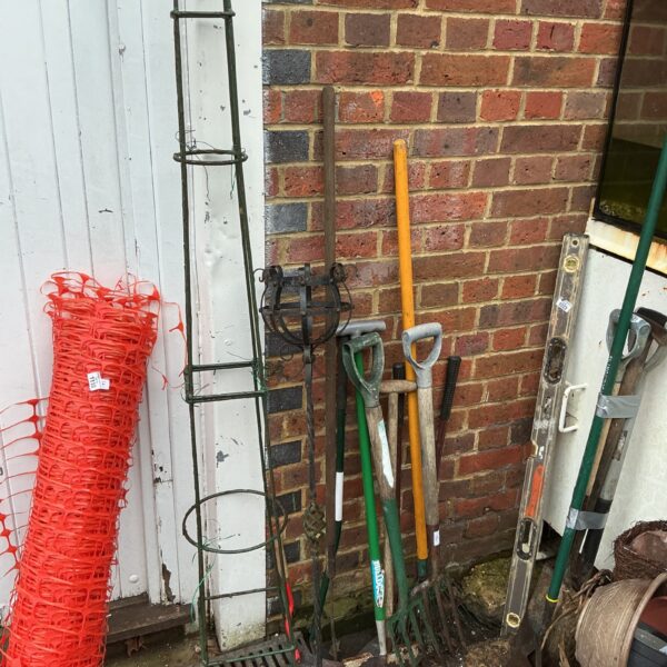 Vintage garden tools and metal plant support for climbing plants.