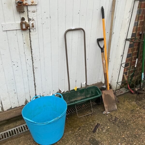Selection of used garden tools and blue tubs for gardening.