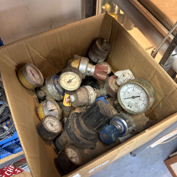 Assorted vintage gas bottle regulators in a cardboard box.