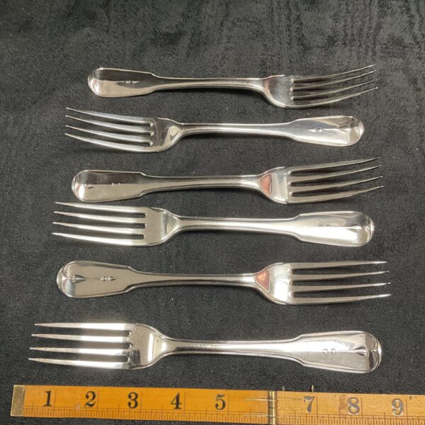 Group of six antique Georgian silver forks on black background.