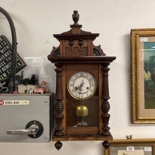 Antique German wall clock with Roman numerals and pendulum.
