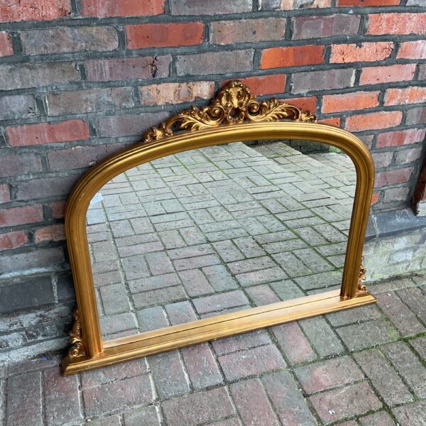 Large gilt overmantle mirror with ornate detailing.