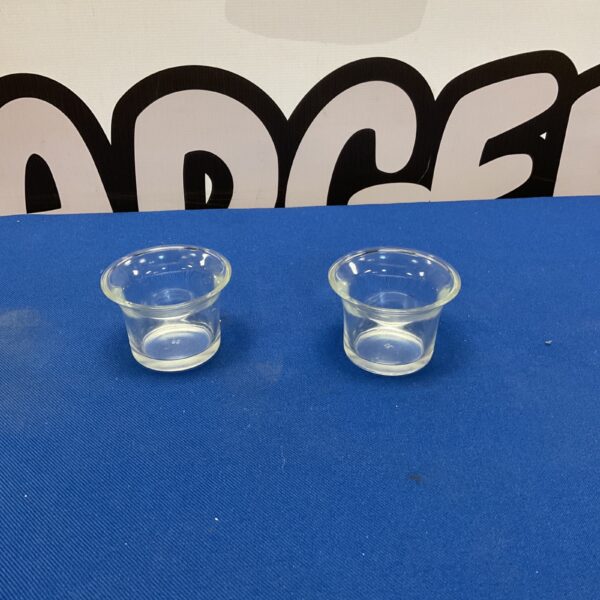 Two clear glass candle holders on a blue surface.