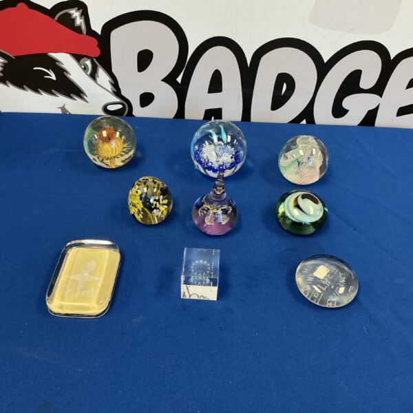 Collection of colourful glass paperweights on a dark surface.