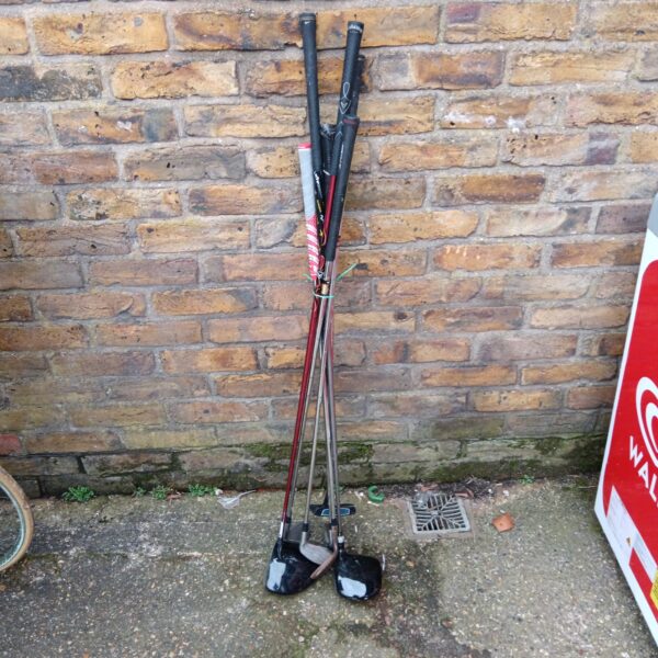 Golf club selection leaning against a brick wall.