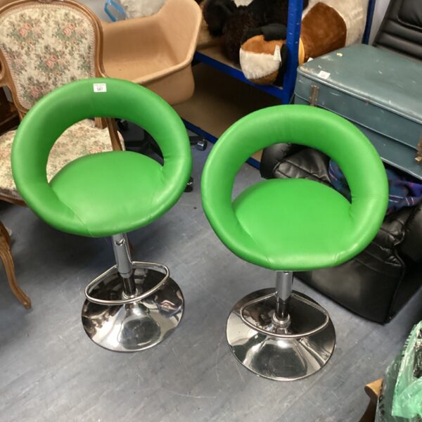 Two green bar stools with chrome frames and adjustable height.